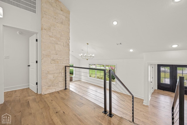 corridor featuring wood-type flooring, an upstairs landing, visible vents, and a healthy amount of sunlight
