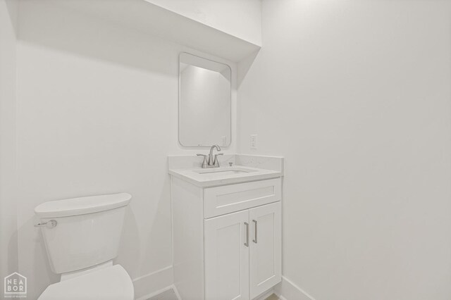 half bath featuring toilet, vanity, and baseboards