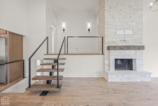 stairway with wood finished floors, a fireplace, a high ceiling, and baseboards