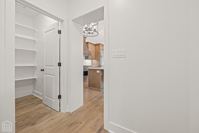 corridor featuring a chandelier and light wood-style floors