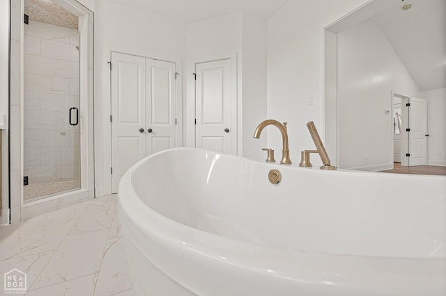 bathroom featuring a shower stall, a soaking tub, and marble finish floor