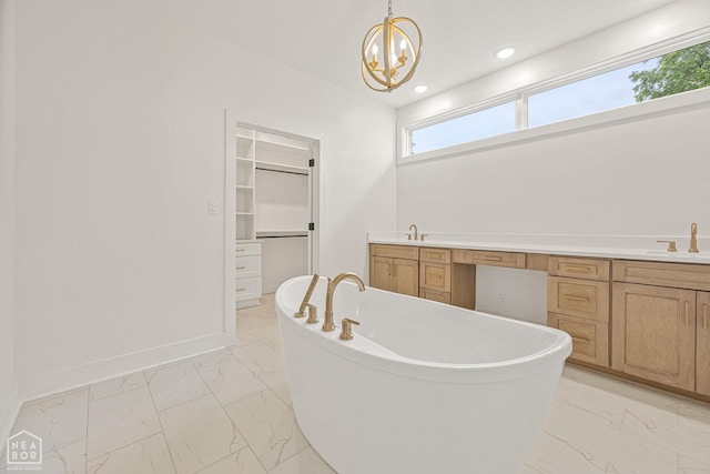 full bathroom with baseboards, a sink, a soaking tub, a walk in closet, and marble finish floor