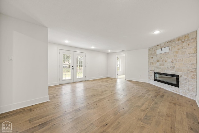 unfurnished living room with recessed lighting, light wood-style floors, baseboards, and a stone fireplace