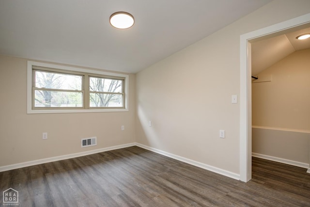 spare room with visible vents, baseboards, dark wood-style floors, and vaulted ceiling
