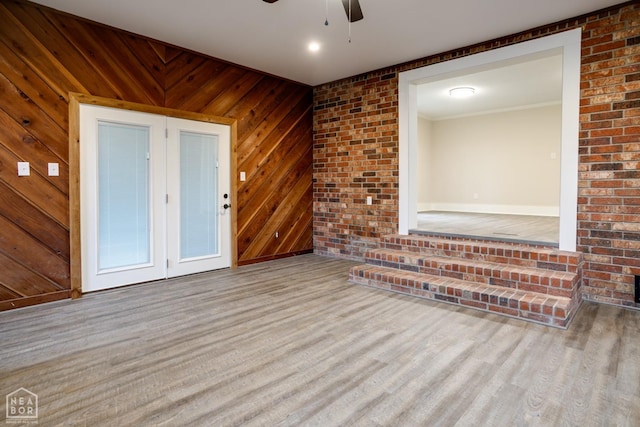 empty room featuring wood walls, wood finished floors, ornamental molding, and ceiling fan