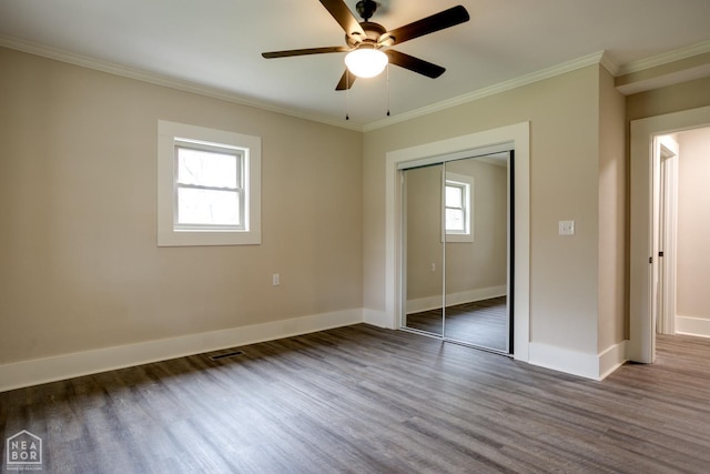unfurnished bedroom with ornamental molding, baseboards, a closet, and wood finished floors