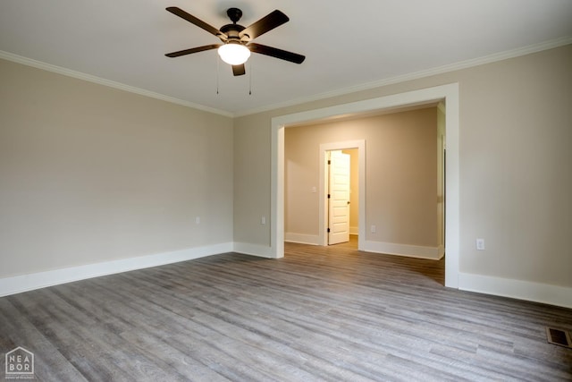 spare room with baseboards, ornamental molding, a ceiling fan, visible vents, and wood finished floors
