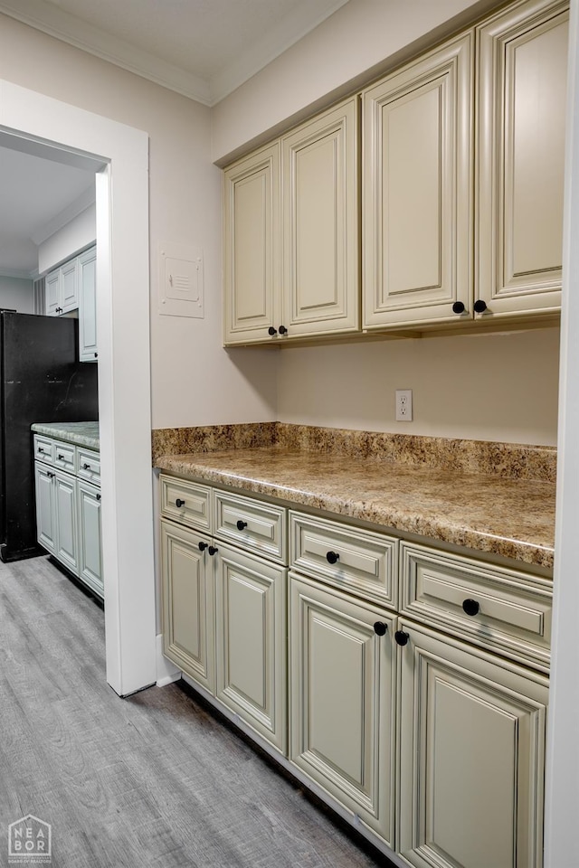kitchen with light wood-style floors, freestanding refrigerator, ornamental molding, and cream cabinetry