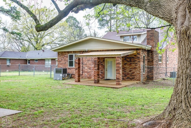 rear view of property featuring a yard, fence, brick siding, and a patio