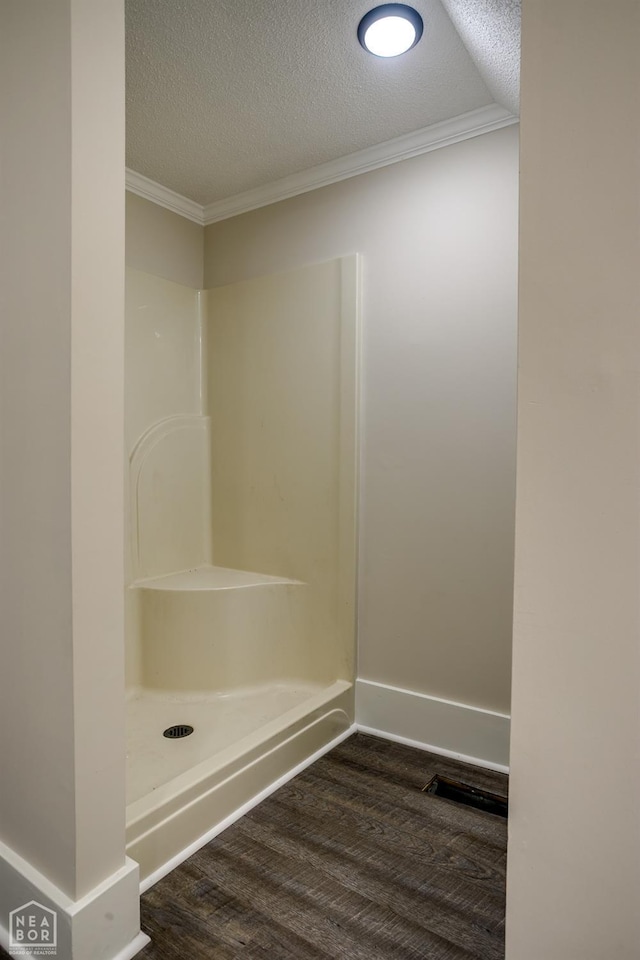 full bathroom with walk in shower, a textured ceiling, ornamental molding, and wood finished floors