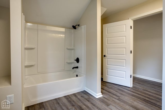 bathroom with baseboards, lofted ceiling, wood finished floors, and shower / bathtub combination