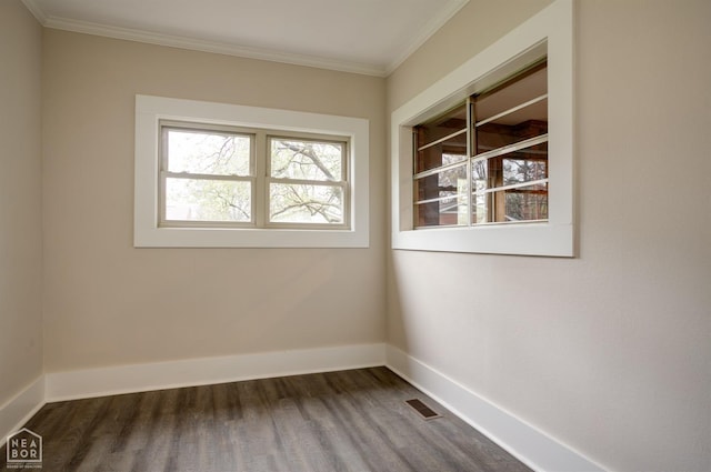 empty room featuring ornamental molding, visible vents, baseboards, and dark wood finished floors