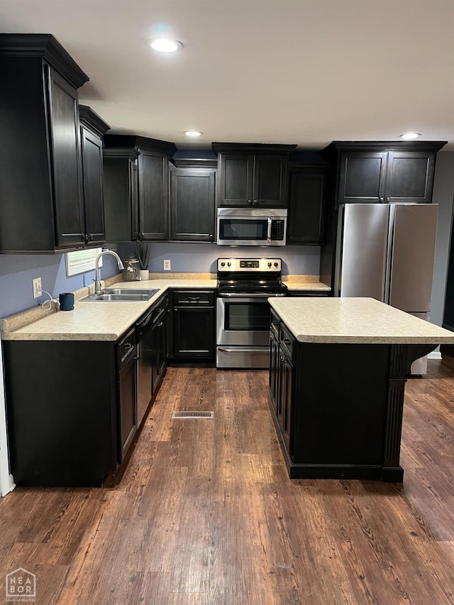 4903 Wise St, Paragould, AR 72450 - kitchen with appliances with stainless steel finishes, dark cabinetry, a sink, a kitchen island, and light countertops