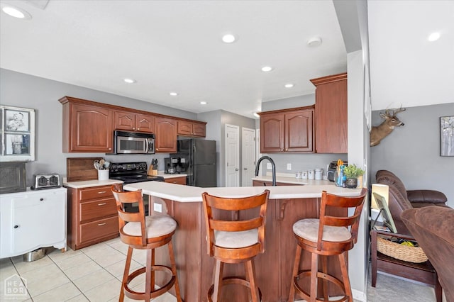 2105 Quarry Cv, Jonesboro, AR 72404 - kitchen with black appliances, a peninsula, light countertops, recessed lighting, and light tile patterned floors