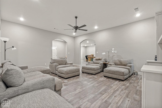 living area featuring visible vents, arched walkways, a ceiling fan, recessed lighting, and light wood finished floors