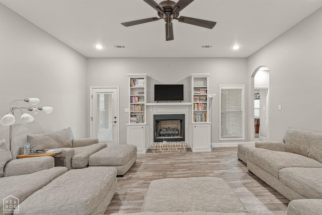 living room featuring visible vents, a ceiling fan, arched walkways, and light wood finished floors