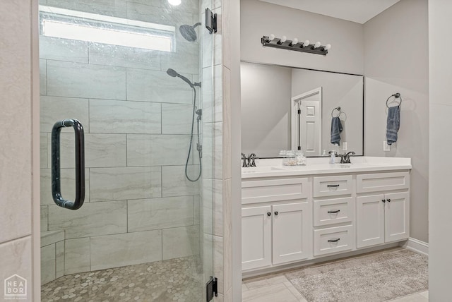 bathroom with a shower stall, double vanity, and a sink