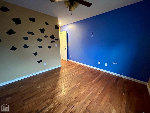 spare room featuring wood finished floors, baseboards, and a ceiling fan