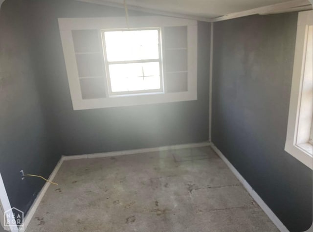 spare room with baseboards and lofted ceiling