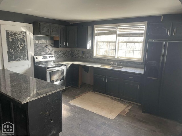 kitchen featuring dark stone counters, electric range, a sink, black fridge with ice dispenser, and decorative backsplash