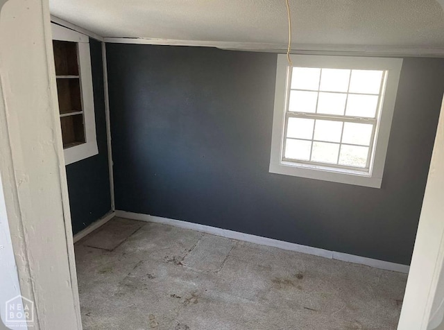 empty room with a textured ceiling and baseboards