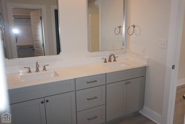 full bathroom featuring double vanity, a sink, and baseboards