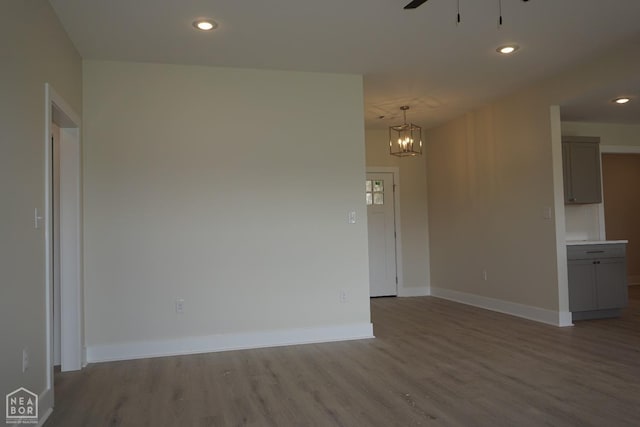 spare room with recessed lighting, baseboards, wood finished floors, and ceiling fan with notable chandelier