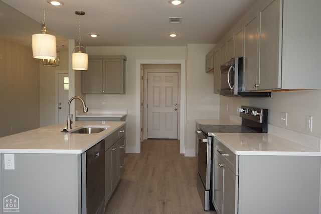 kitchen featuring appliances with stainless steel finishes, a sink, light wood finished floors, visible vents, and gray cabinetry