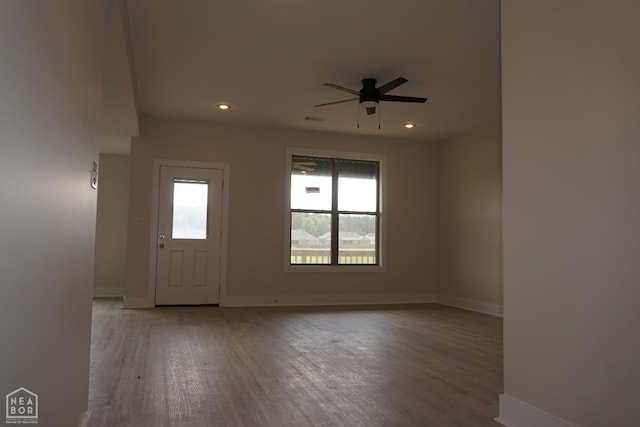 empty room featuring a healthy amount of sunlight, baseboards, ceiling fan, and wood finished floors
