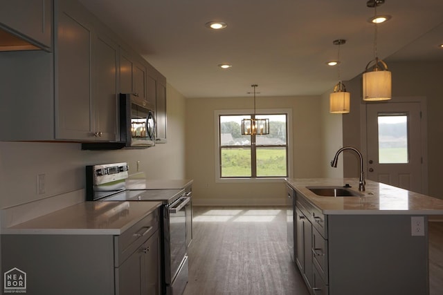 kitchen with wood finished floors, a sink, baseboards, stainless steel appliances, and recessed lighting