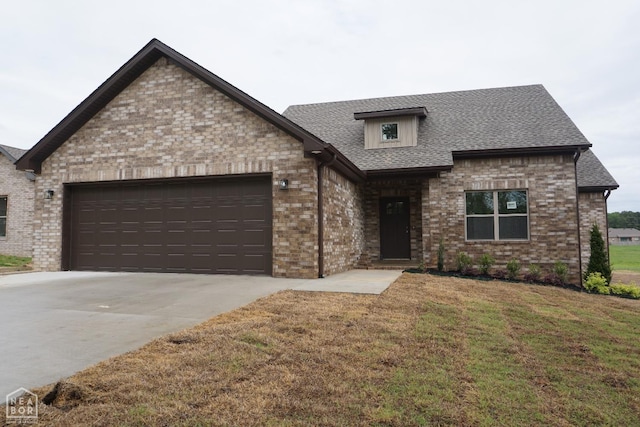 view of front of home with driveway, roof with shingles, brick siding, a front lawn, and an attached garage
