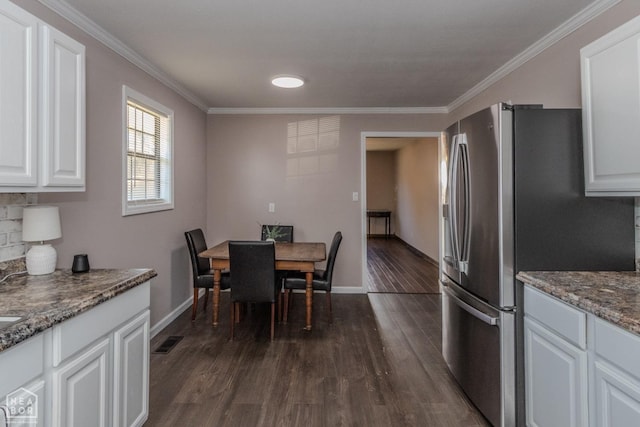 dining space with dark wood-type flooring, visible vents, baseboards, and ornamental molding