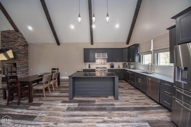 kitchen featuring vaulted ceiling with beams, under cabinet range hood, a sink, and appliances with stainless steel finishes