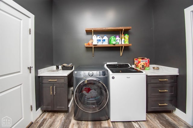 laundry room with wood finished floors, washing machine and dryer, baseboards, and cabinet space