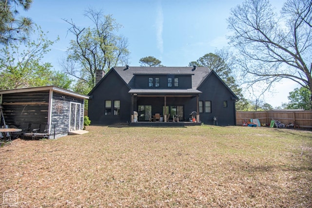 back of house with a yard, roof with shingles, fence, and a chimney
