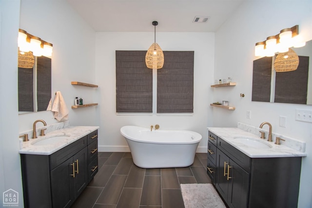 full bath featuring two vanities, a sink, and visible vents