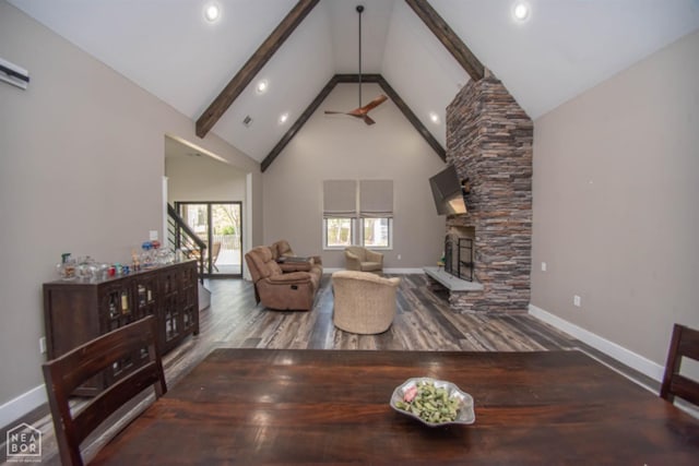 living room with baseboards, a stone fireplace, beamed ceiling, wood finished floors, and high vaulted ceiling