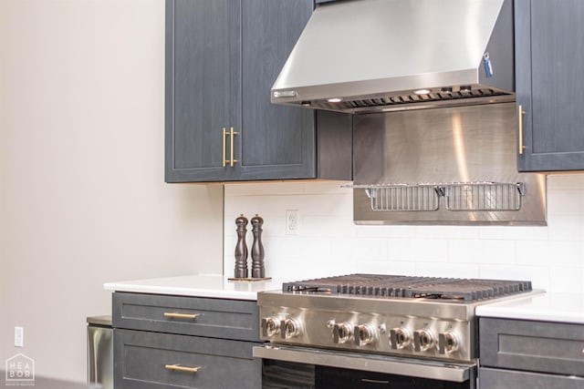 kitchen featuring light countertops, tasteful backsplash, wall chimney exhaust hood, and stainless steel range