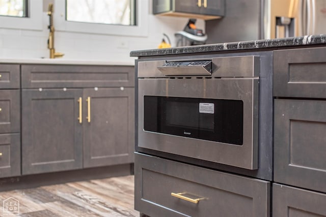 interior details with oven, gray cabinetry, and wood finished floors