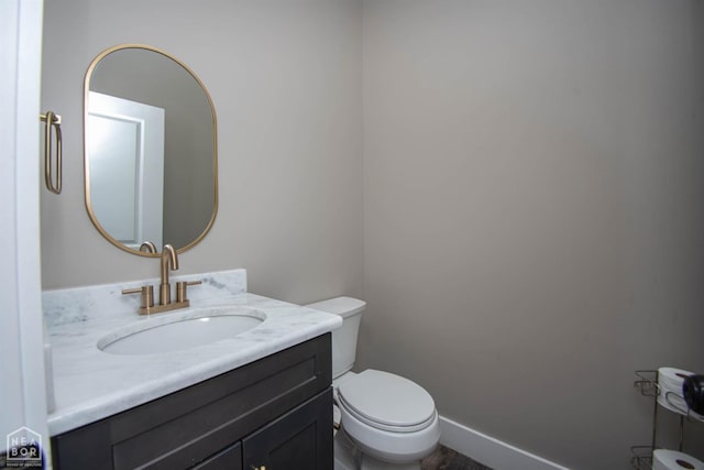 bathroom with toilet, vanity, and baseboards