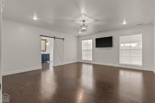 unfurnished living room with baseboards, dark wood-style floors, crown molding, a barn door, and visible vents