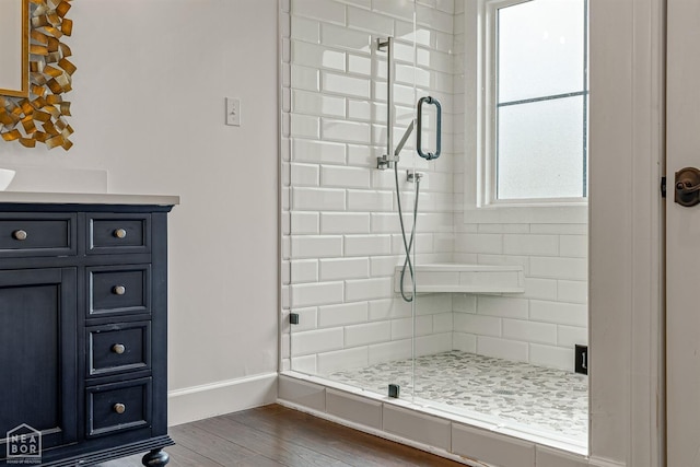 bathroom with a stall shower, wood finished floors, and baseboards