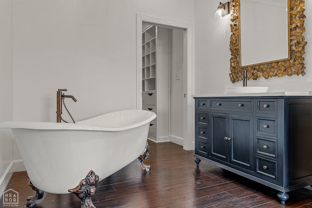 bathroom with a freestanding bath, wood finished floors, vanity, and baseboards
