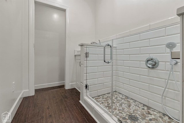 bathroom with baseboards, a shower stall, and wood finished floors