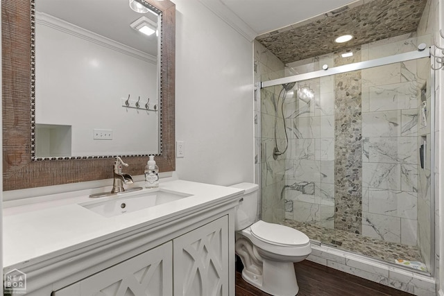 bathroom featuring toilet, crown molding, vanity, wood finished floors, and a stall shower