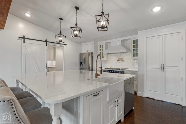 kitchen with dark wood-type flooring, a barn door, custom exhaust hood, appliances with stainless steel finishes, and decorative backsplash