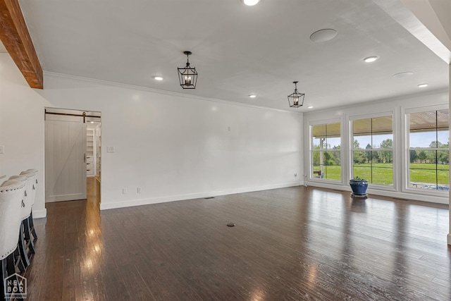 unfurnished living room featuring crown molding, recessed lighting, a barn door, and dark wood finished floors