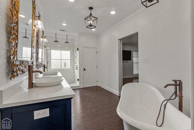 full bathroom featuring double vanity, a soaking tub, crown molding, visible vents, and a sink