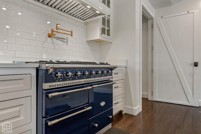kitchen with custom range hood, glass insert cabinets, backsplash, dark wood finished floors, and range with two ovens