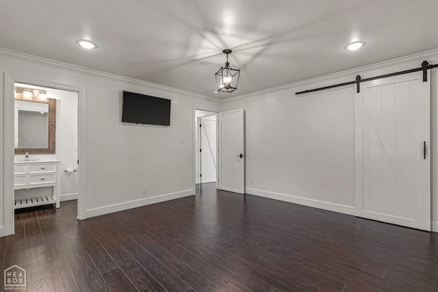 interior space with crown molding, dark wood-style flooring, baseboards, and a barn door